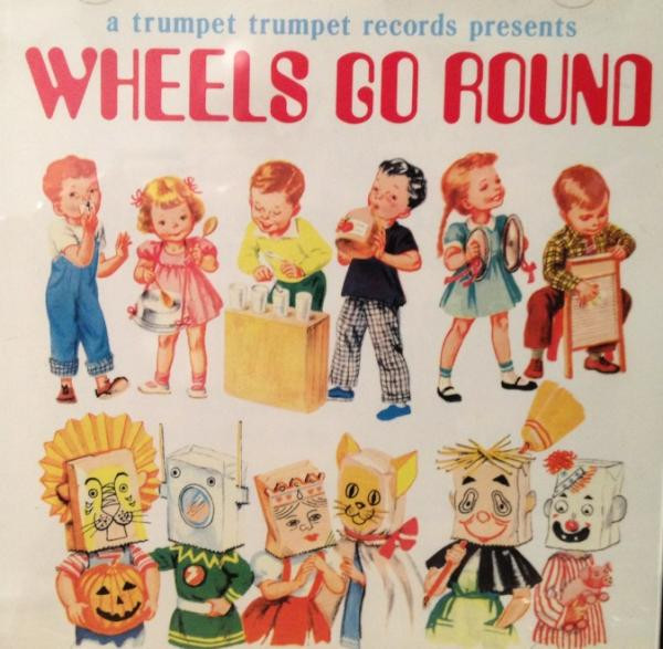 Cover of Wheels Go Round. At the very top, some falvor text saying: A Trumpet Trumpet Records Presents, Wheels Go Round. Below that, early-mid 20th century style illustrations of six children playing homemade instruments. Below that, six more illustrations of children, this time in homemade costumes.